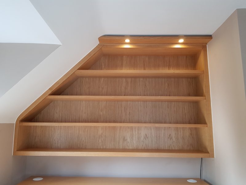 Bespoke bookshelf with integrated lighting maximises the use of the space under a sloped ceiling