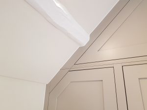 Cabinetry scribed to fit perfectly to the angled ceiling and feature beams.